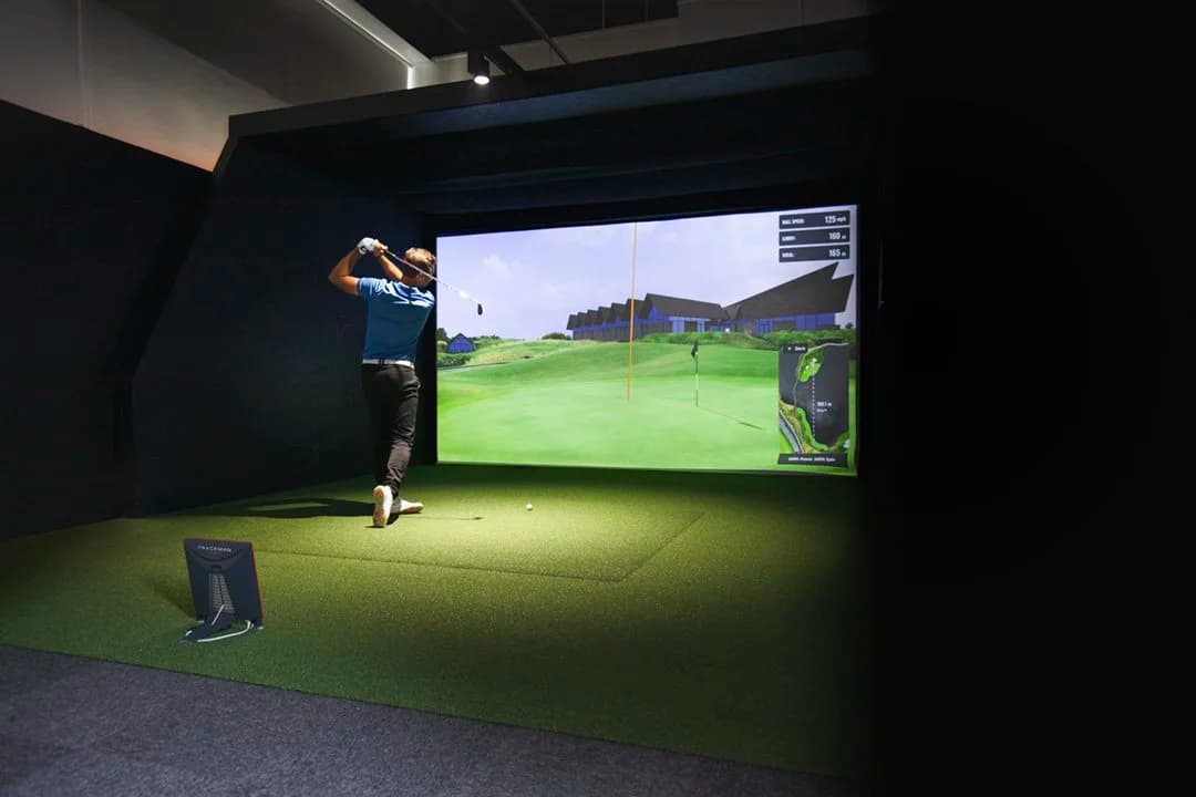 Player swinging in a TrackMan simulator with course data visible on screen