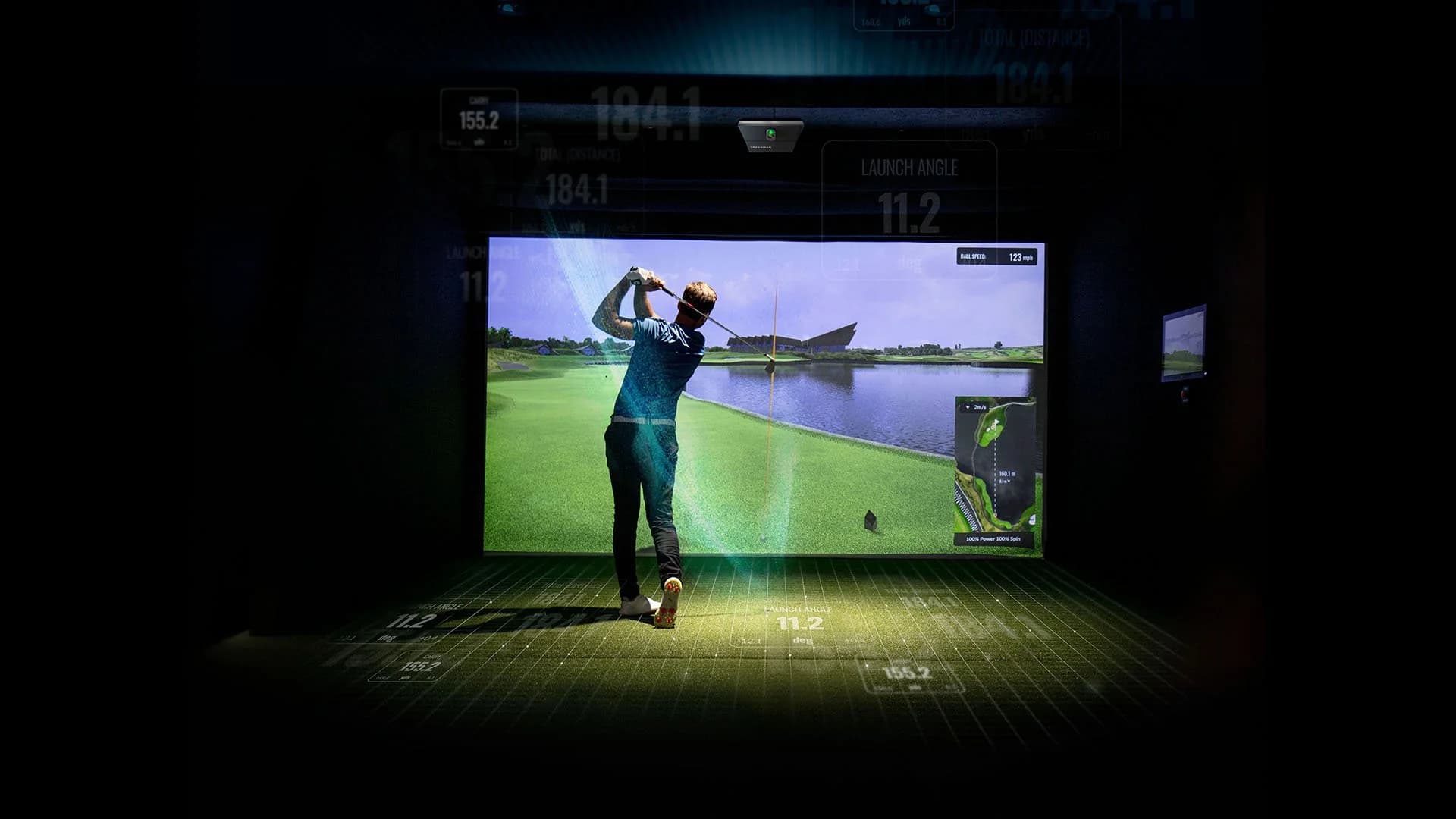 Wide view of a TrackMan iO simulator bay with overhead launch monitor